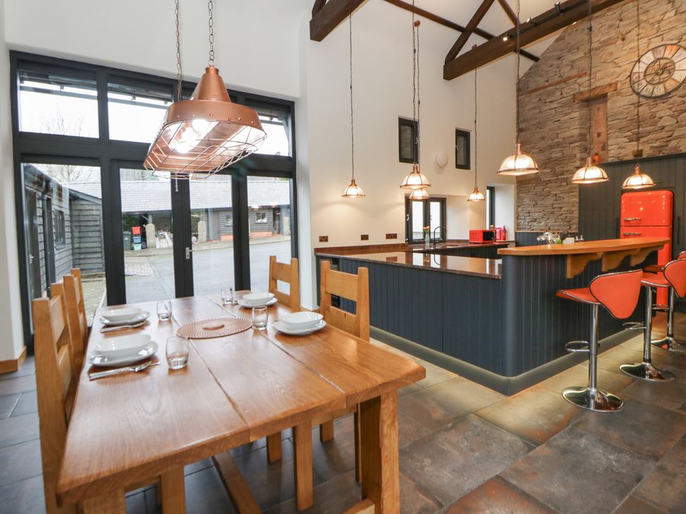 A kitchen with a dining table and bar stools at The Barn at Sunny Barn in Brecon