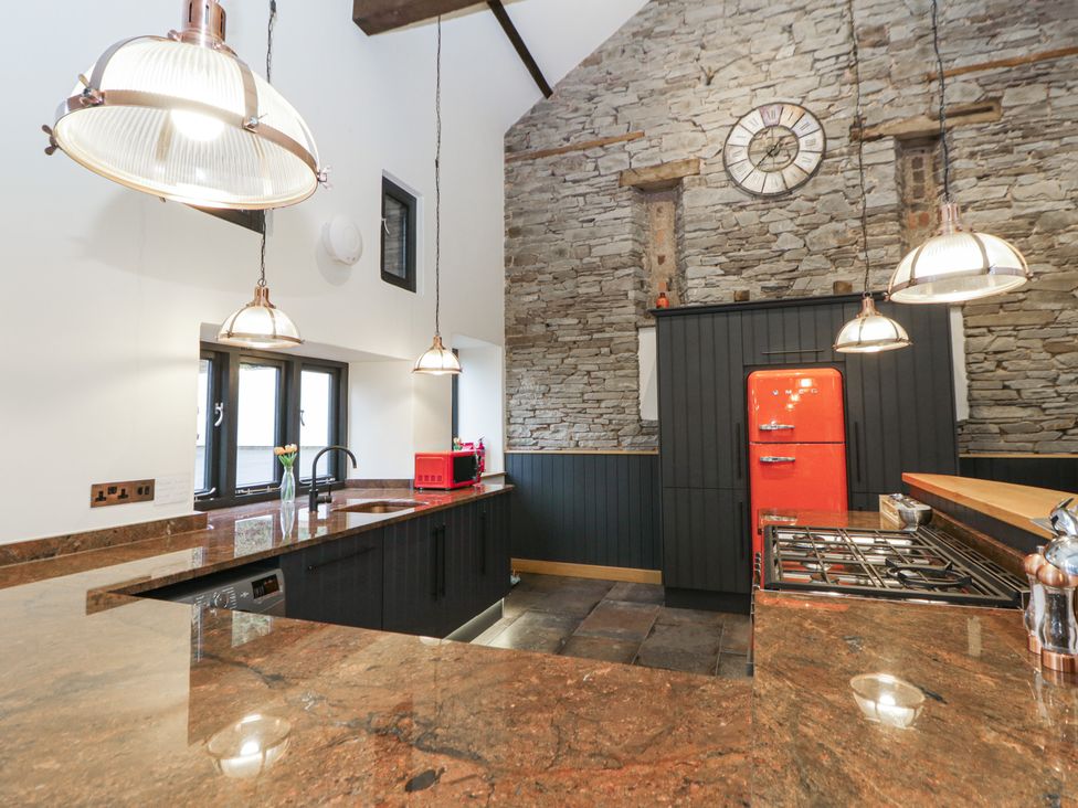 A kitchen with a red fridge and stone wall at The Barn at Sunny Barn in Brecon