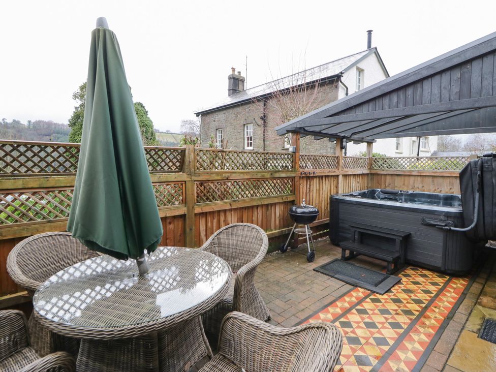 An outdoor patio with a hot tub and seating area at The Barn at Sunny Barn Brecon