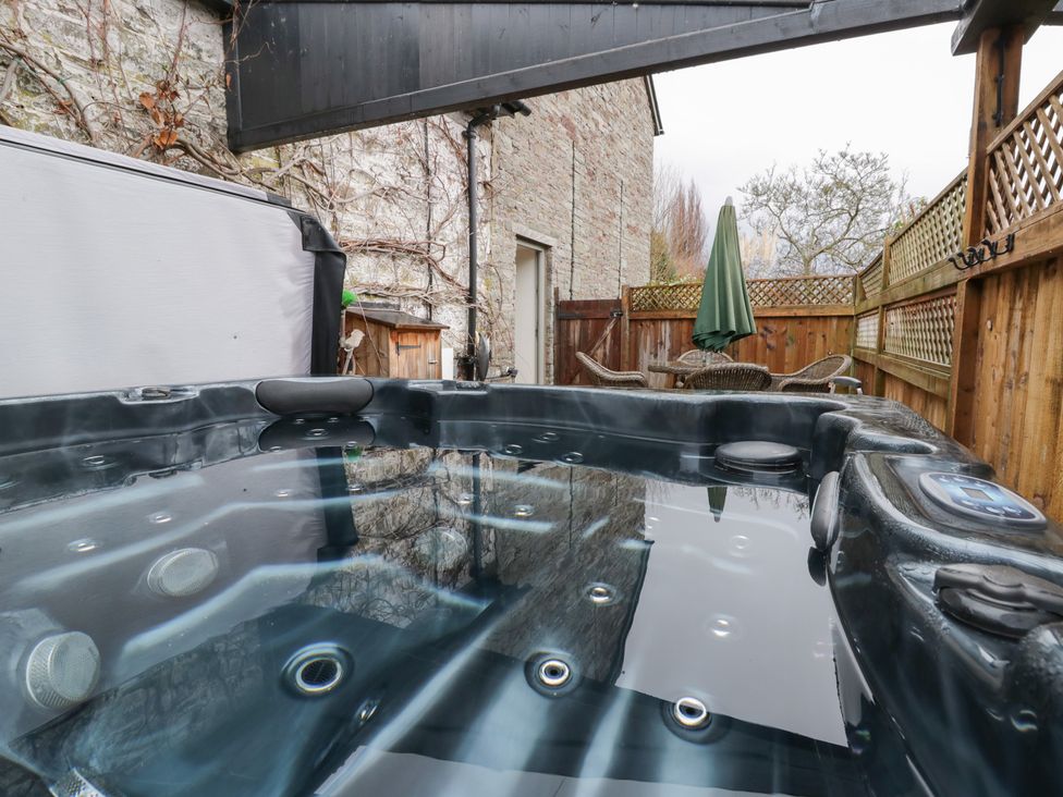 An outdoor area with a hot tub and patio furniture at The Barn at Sunny Barn, Brecon