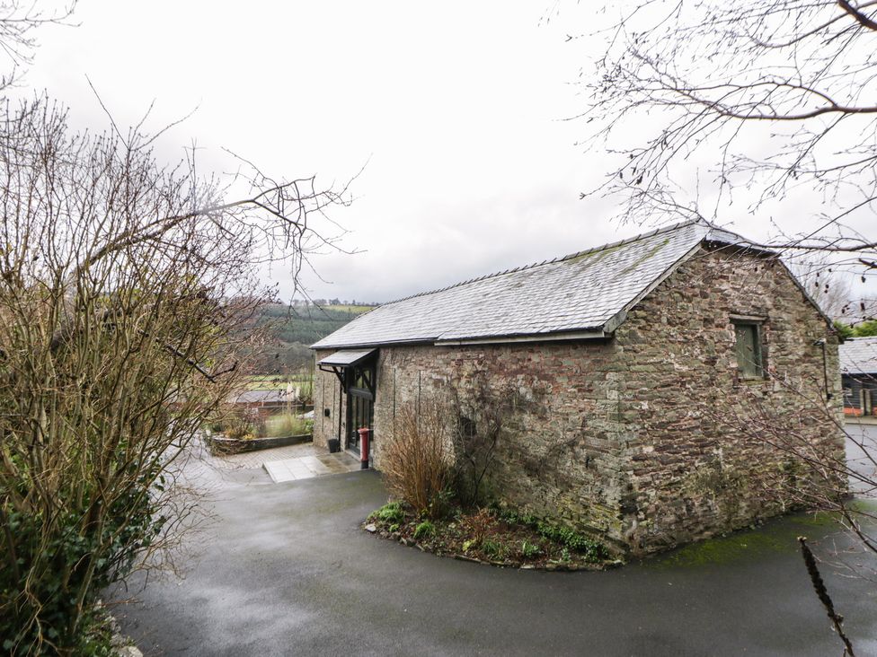 A stone building with a roof and pathway at The Barn at Sunny Barn Brecon