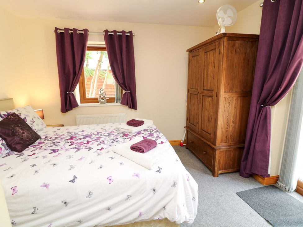A bedroom with a bed and wardrobe at Sunnyside Lodge in Thorpe-On-The-Hill