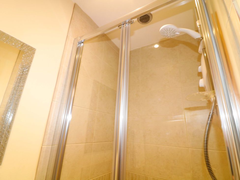 A shower enclosure with glass doors and shower head at Sunnyside Lodge in Thorpe-On-The-Hill