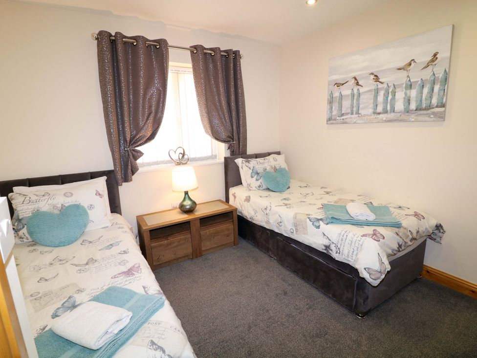 A bedroom with two beds and a bedside table at Sunnyside Lodge in Thorpe-On-The-Hill