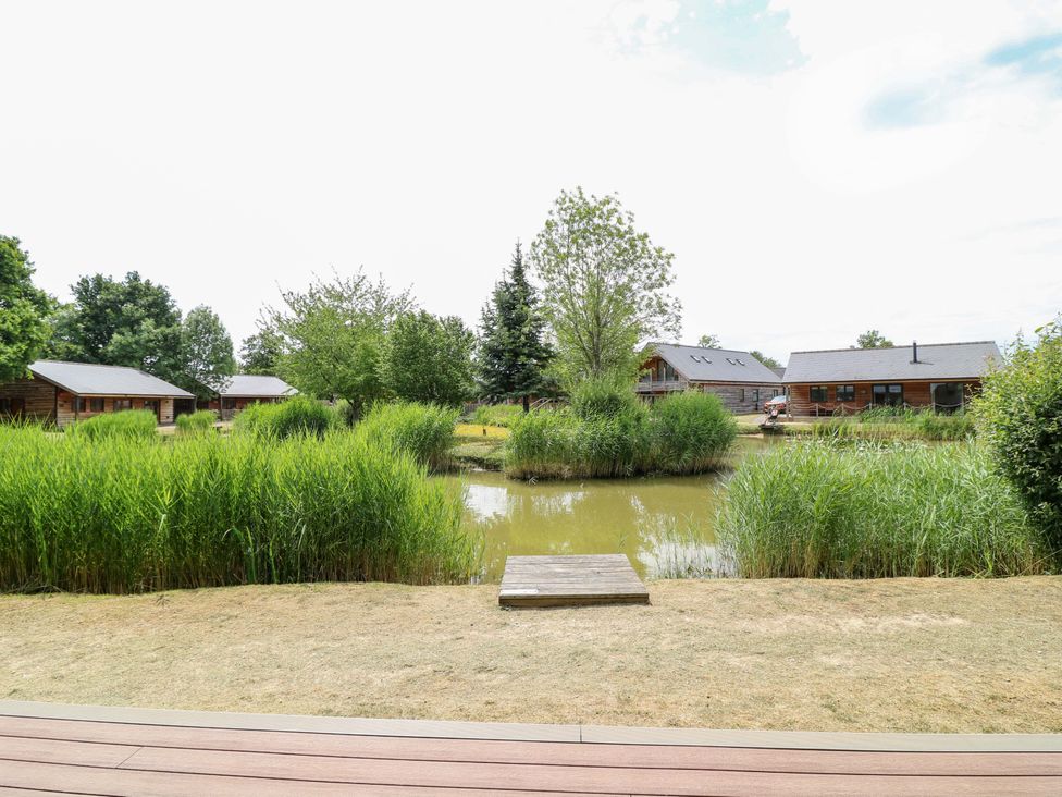 An outdoor area with cabins and a pond at Sunnyside Lodge in Thorpe-On-The-Hill
