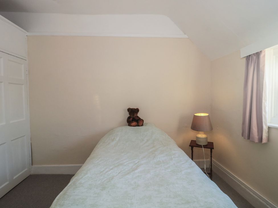 A bedroom with a bed and a teddy bear on it at Vine Cottage in Alderton