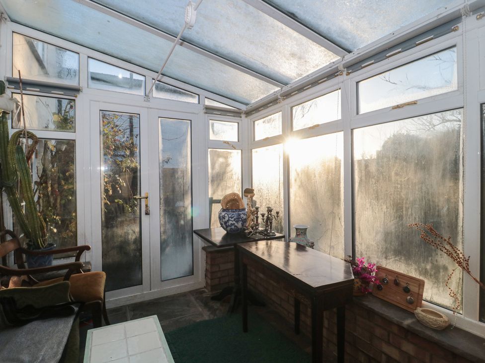 A conservatory with a table and chairs at Vine Cottage in Alderton