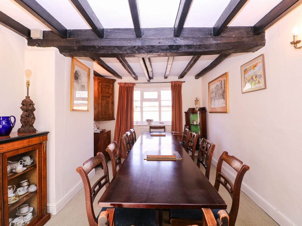 A dining room with a long table and chairs at Vine Cottage in Cheltenham