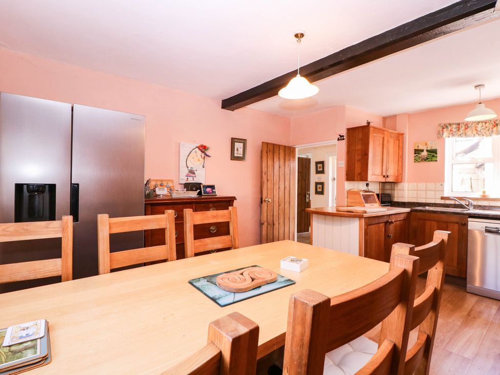 A kitchen with a dining table and refrigerator at Vine Cottage Cheltenham