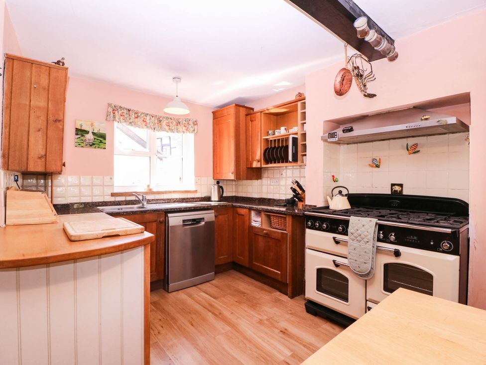 A kitchen with appliances and wooden cabinets at Vine Cottage in Cheltenham