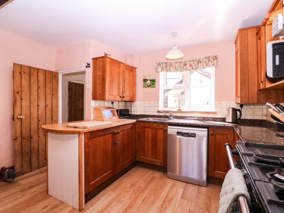 A kitchen with wooden cabinets and a dishwasher at Vine Cottage in Cheltenham