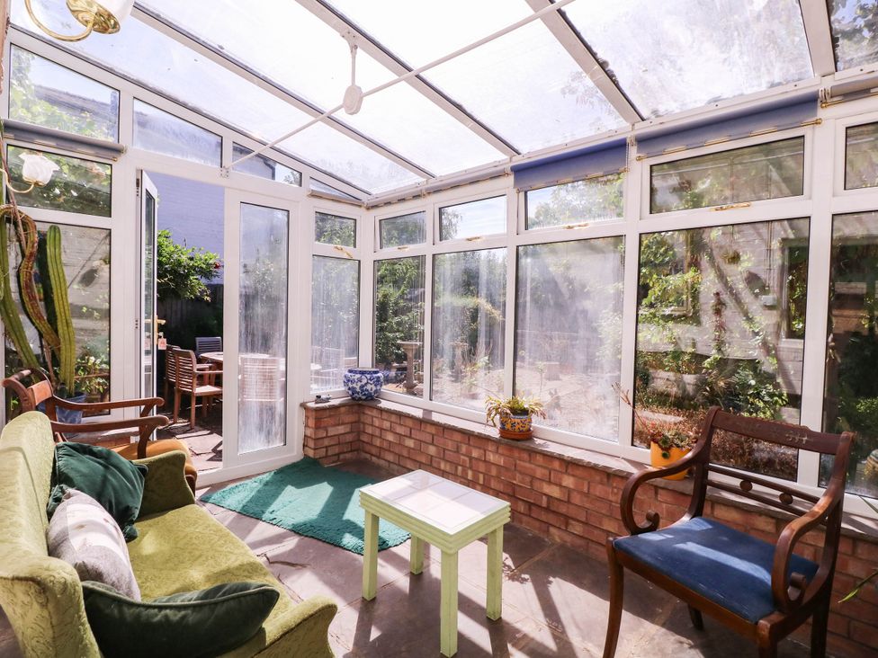 A conservatory with a sofa and a table at Vine Cottage in Cheltenham