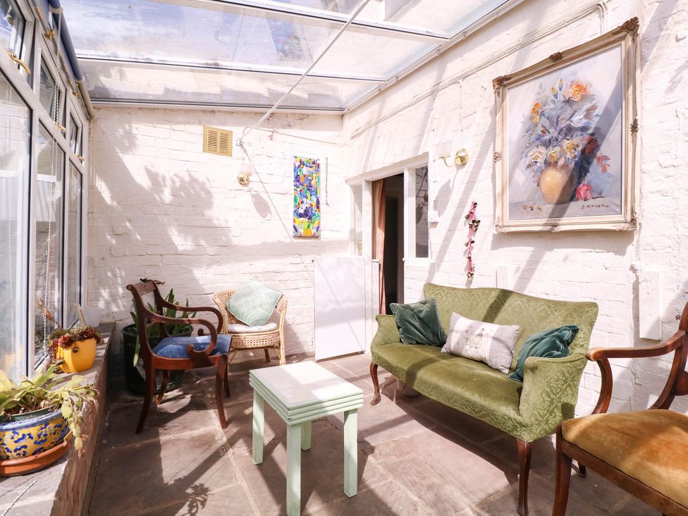 A conservatory with seating and a table at Vine Cottage in Cheltenham