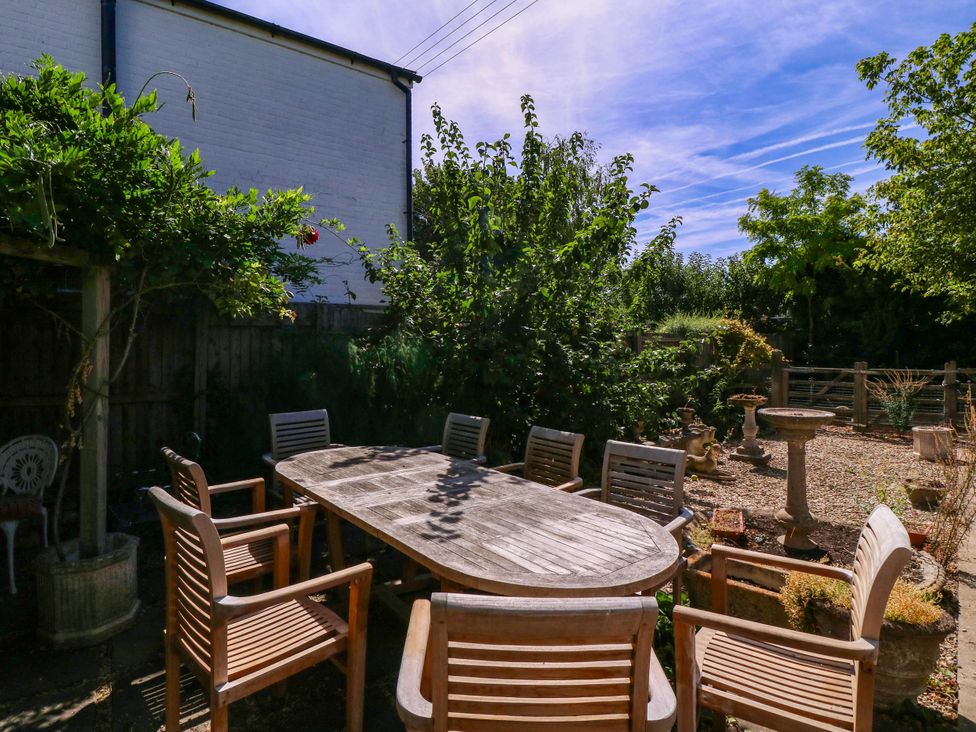 A garden with a wooden table and chairs at Vine Cottage Cheltenham