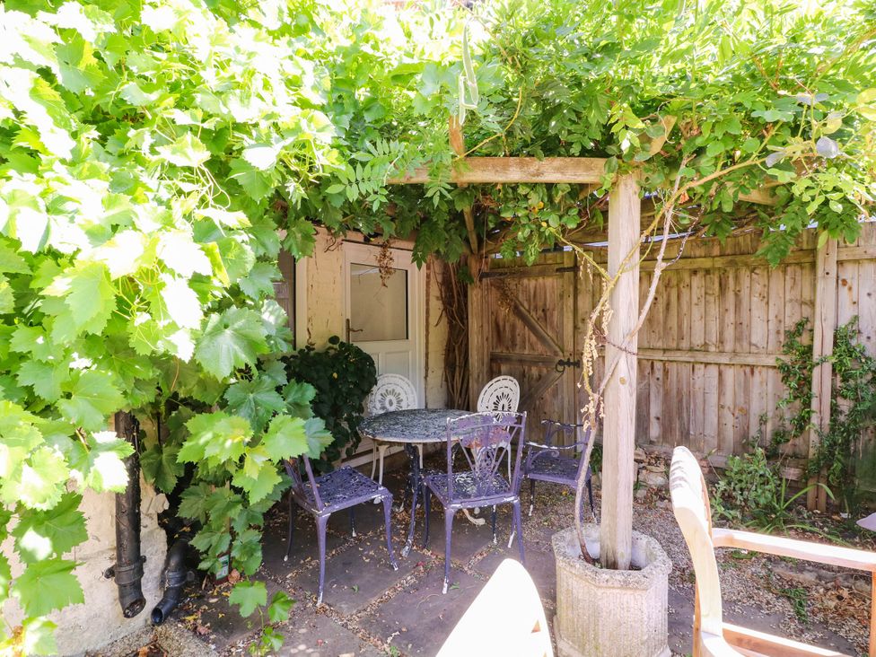 A garden with a table and chairs surrounded by plants at Vine Cottage in Cheltenham