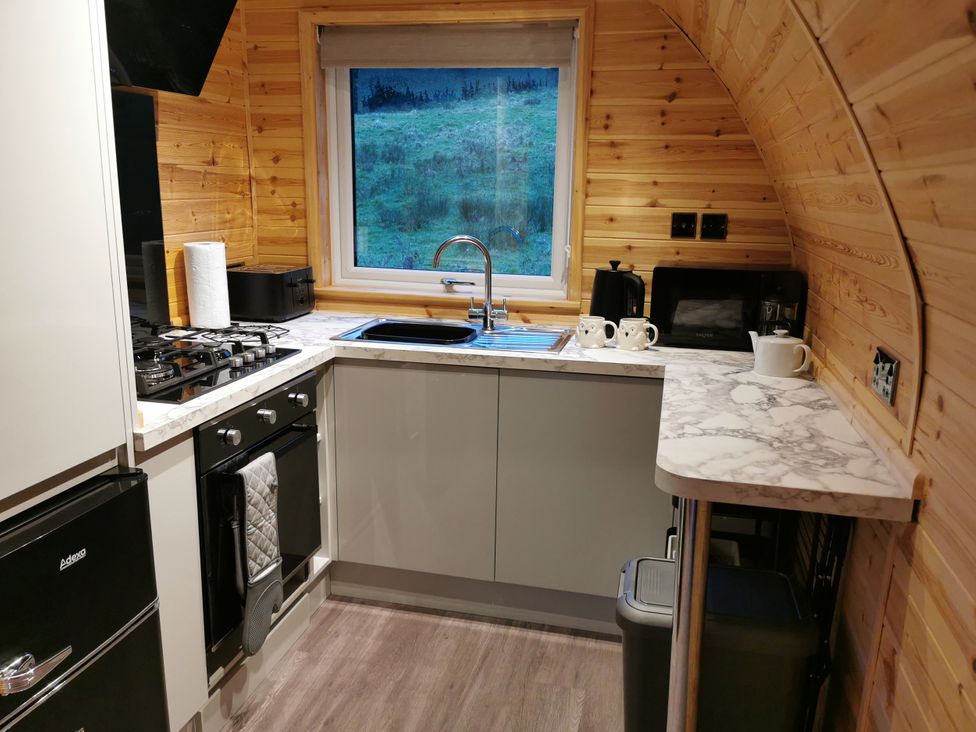 A kitchen with a sink, stove, and window at Lodge 2 Pontyates
