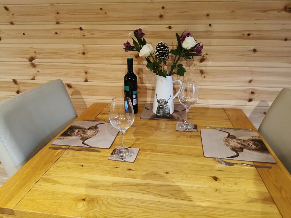 A dining room table set with wine and flowers at Lodge 3 in Pontyates