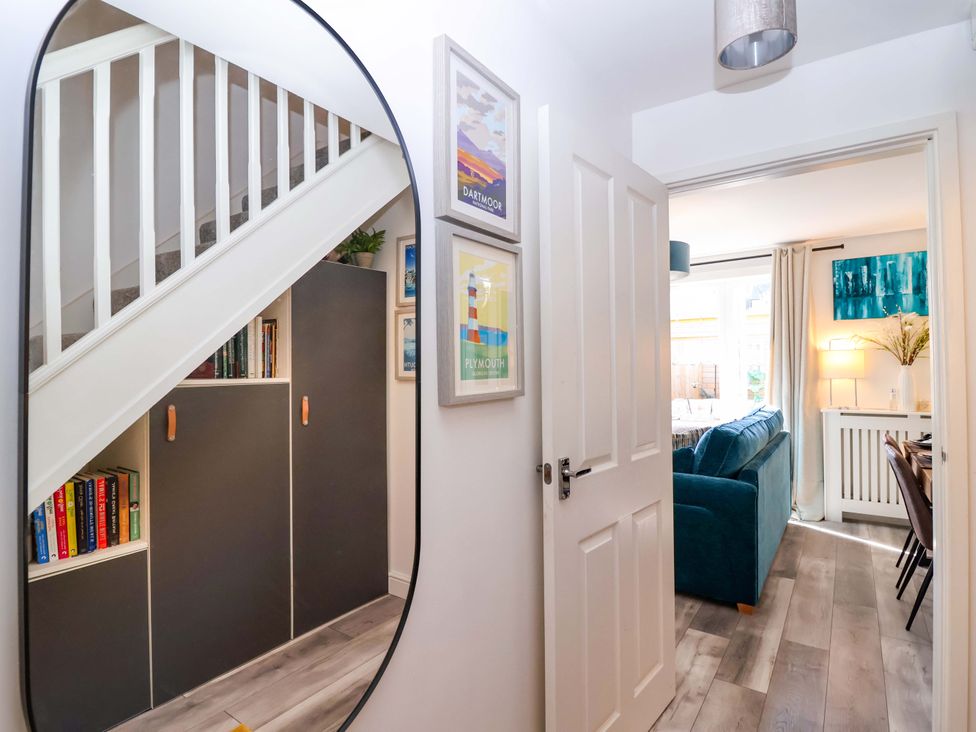 A hallway with a mirror and a cupboard at 21 Olympic Way Plymouth