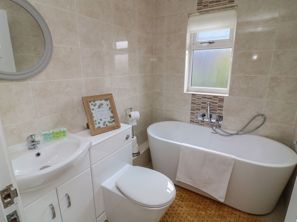 A bathroom with a bathtub, toilet, sink, and mirror at James Ville Marina Lodge 10 in Brigg