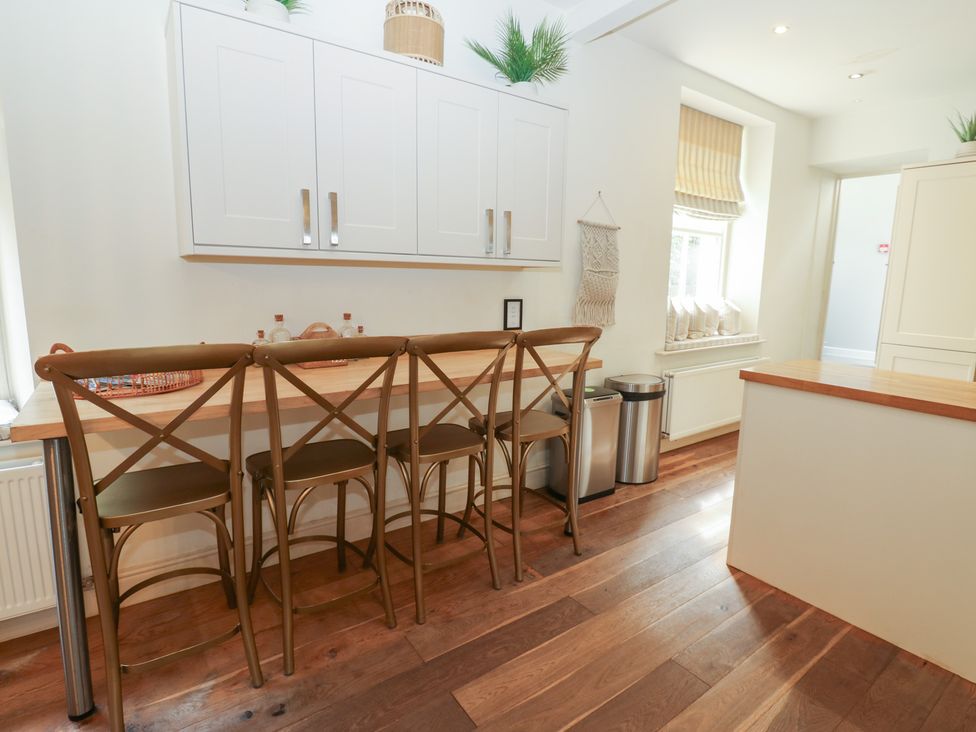 A kitchen with a counter and bar stools at Hampton House in St. Bees
