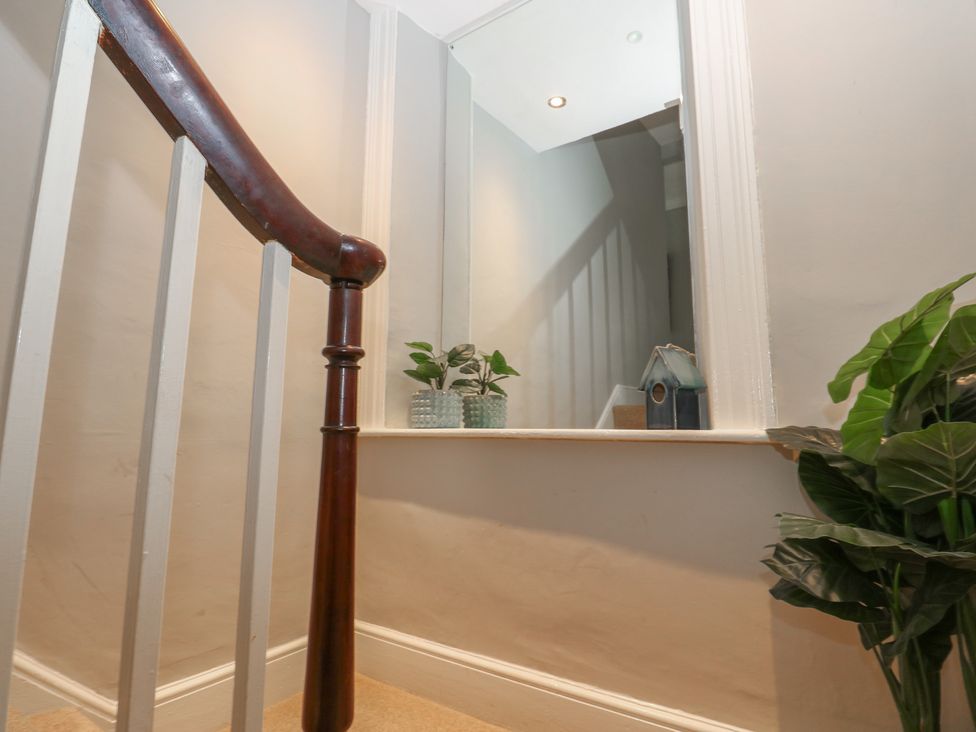 A staircase with a handrail and a mirror in a hallway at Hampton House St. Bees