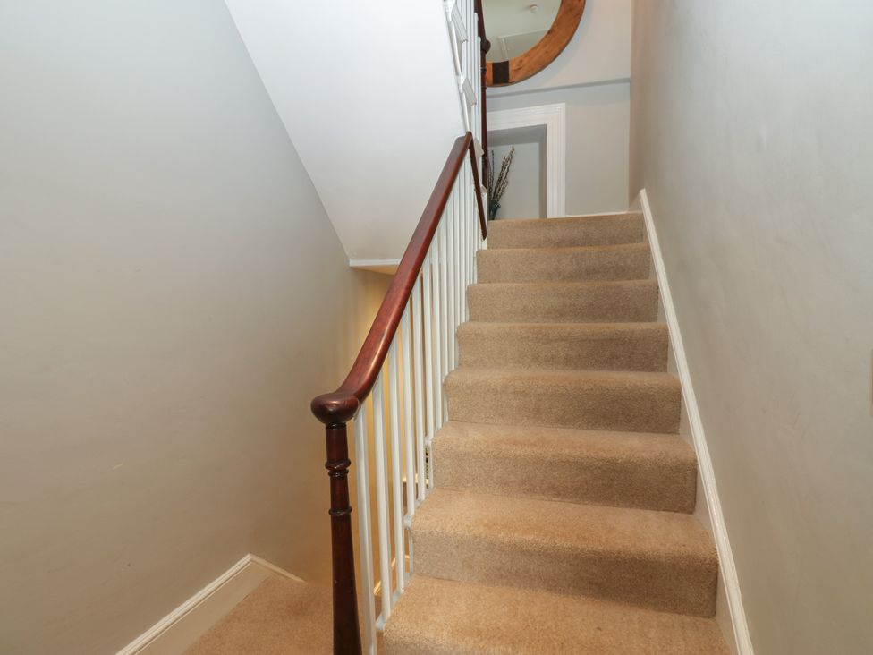 A staircase with carpet and a mirror at Hampton House in St. Bees