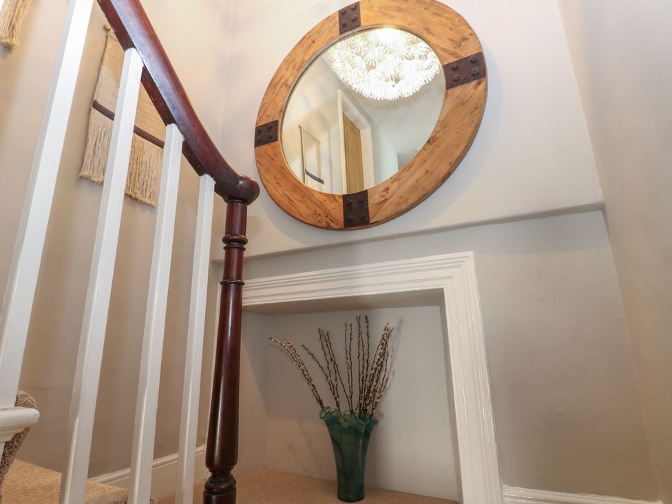 A staircase with a mirror and decorative vase in Hampton House St. Bees