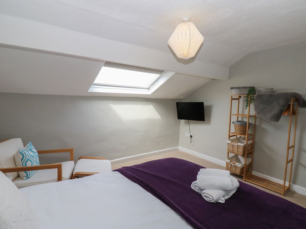 A bedroom with a bed, chair, and shelving unit at Hampton House St. Bees