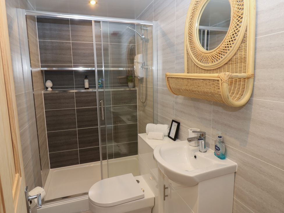 A bathroom with shower, toilet, sink, and mirror at Hampton House St. Bees