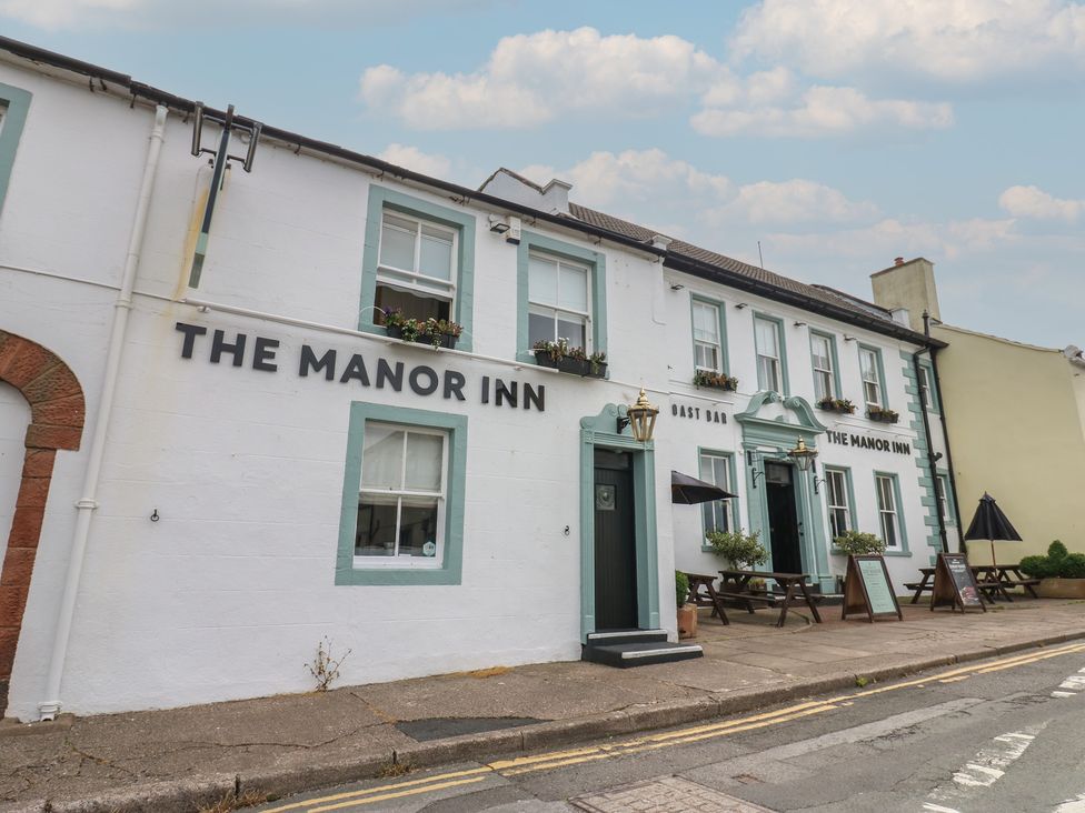 An exterior view of The Manor Inn with outdoor seating at Hampton House in St. Bees