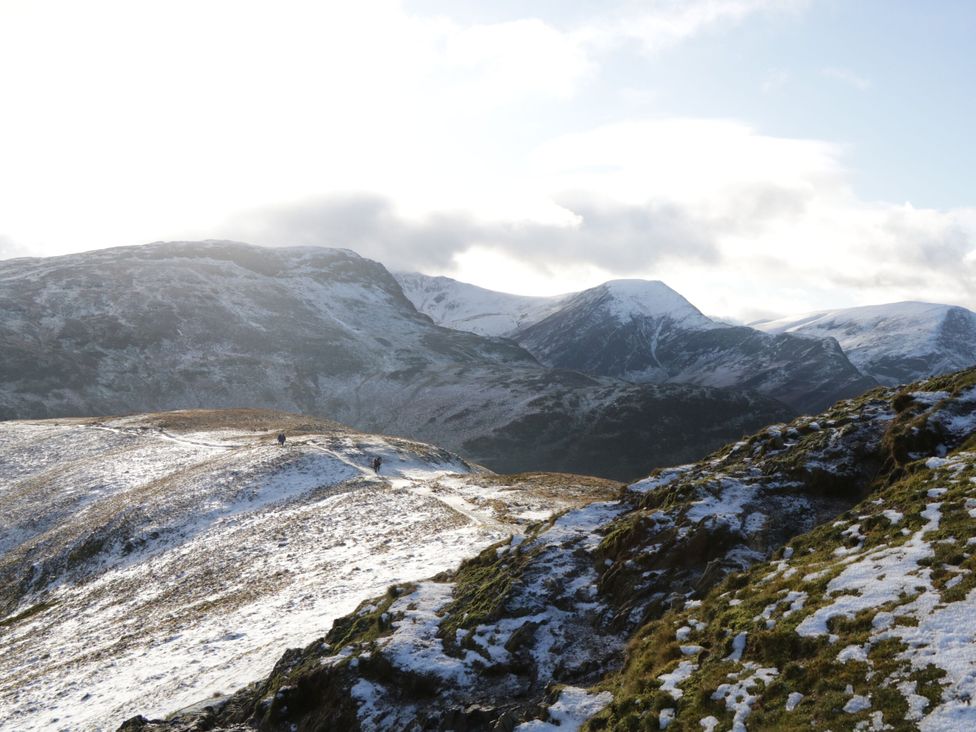 A landscape with snow-covered mountains and hikers at Hampton House St. Bees
