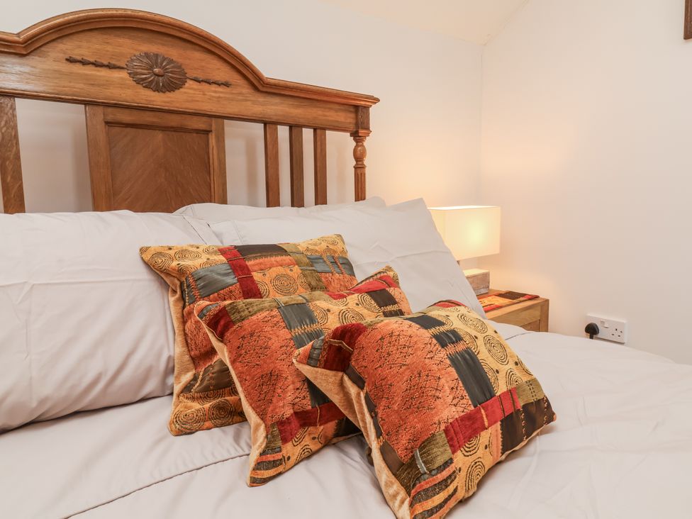 A bed with decorative pillows and a lamp on a bedside table at Lane End in North Molton