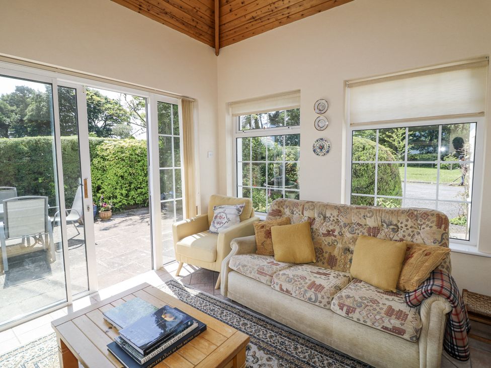 A conservatory with a sofa and armchair at Knockroe Lodge