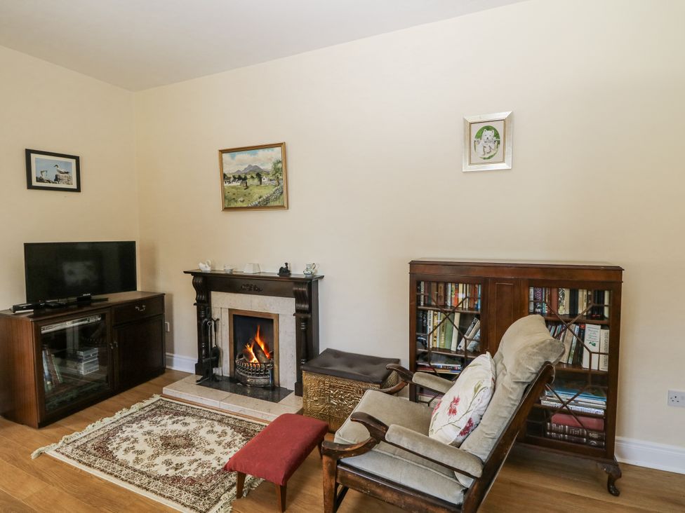 A living room with a fireplace and bookshelves at Knockroe Lodge
