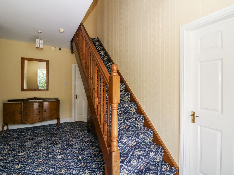 A hallway with a staircase and console table at Knockroe Lodge