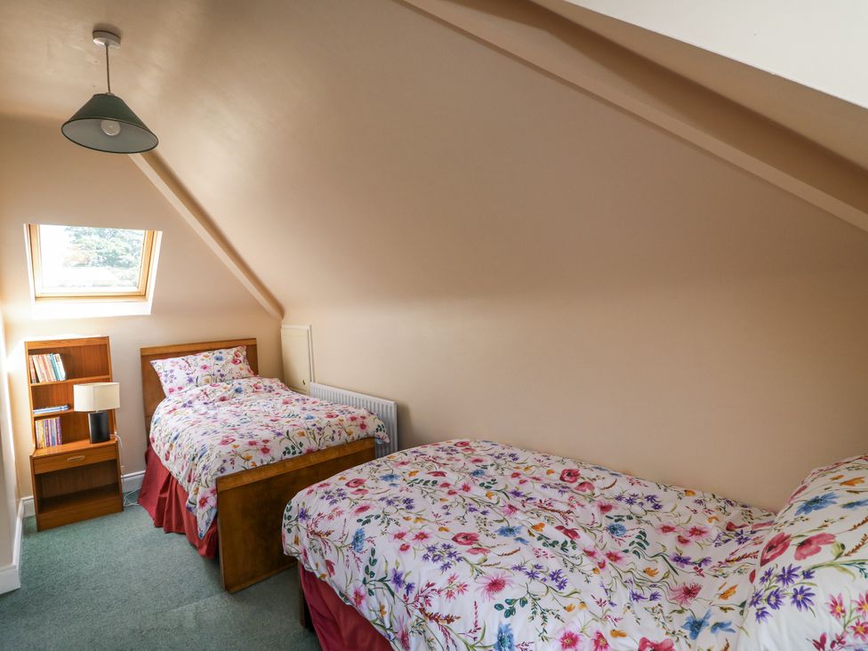 A bedroom with two beds and a bookshelf at Knockroe Lodge