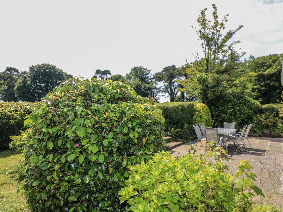 A garden with a table and chairs on a stone patio at Knockroe Lodge 