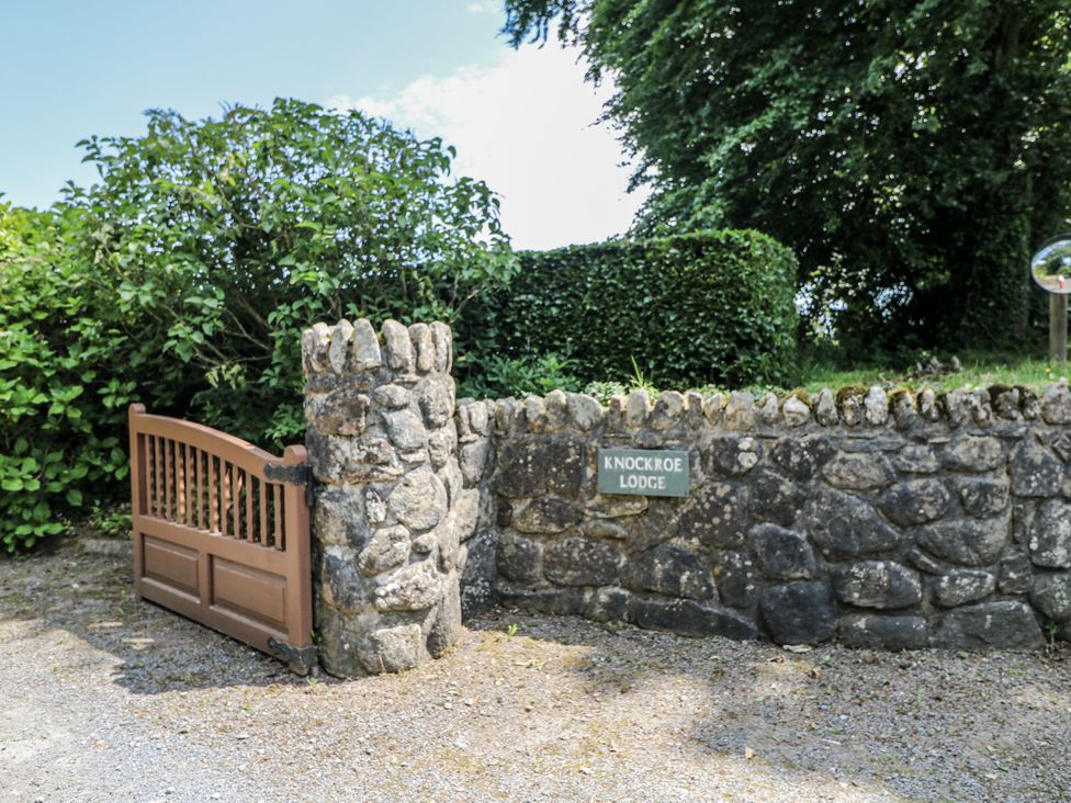 A gate with stone wall and sign at Knockroe Lodge