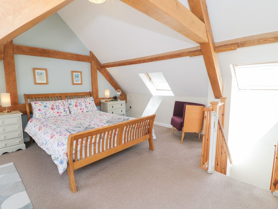 A bedroom with a bed and chair at Woodpecker Cottage in Llangollen