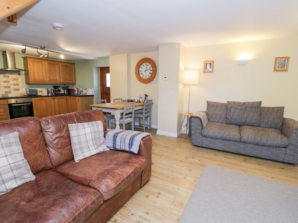 A living room with a sofa and dining area at Owl Cottage in Llangollen