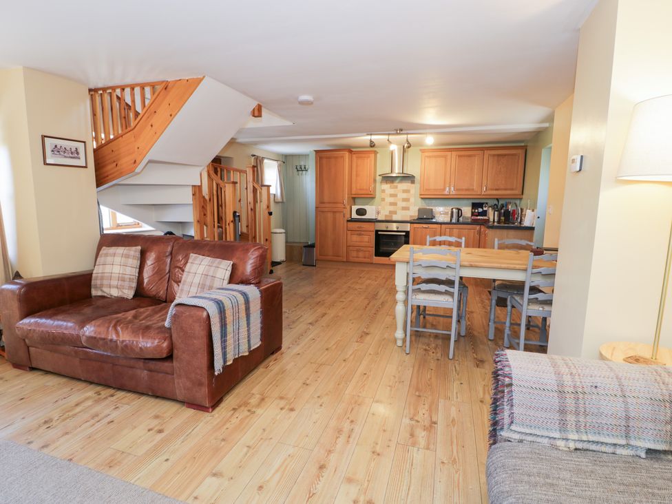 A living room with a sofa and dining area at Owl Cottage in Llangollen