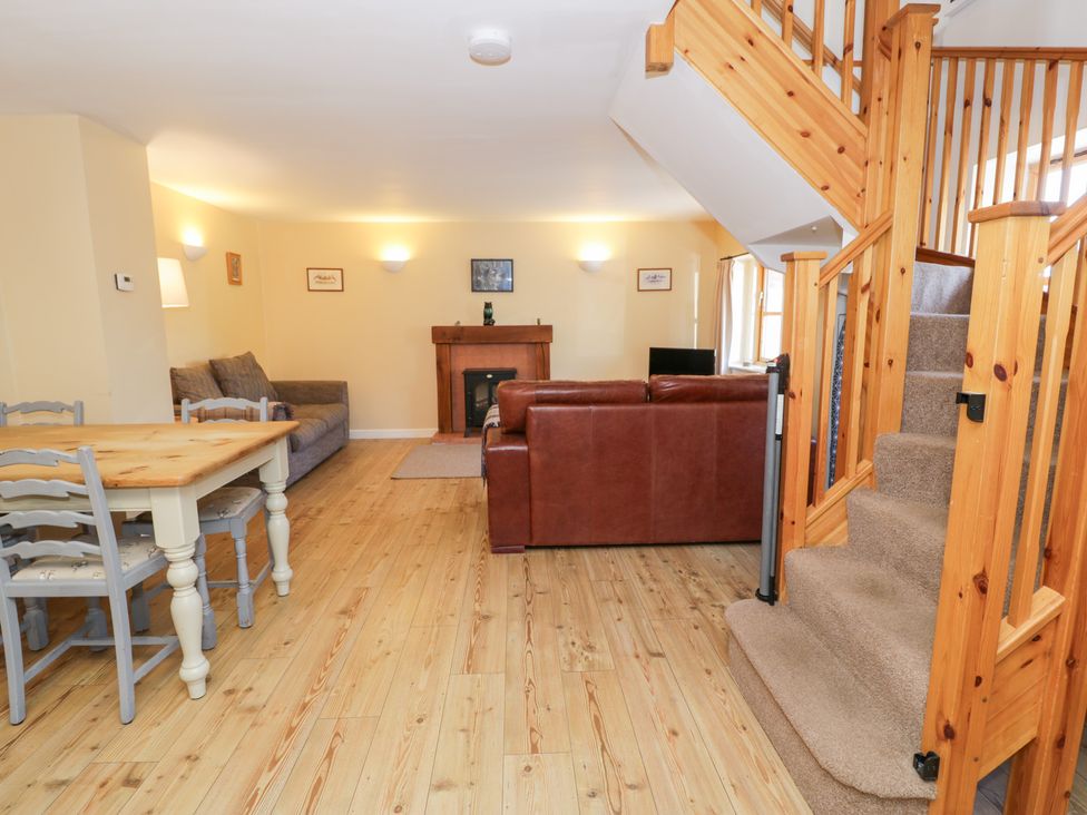 A living room with a sofa, table and chairs at Owl Cottage in Llangollen