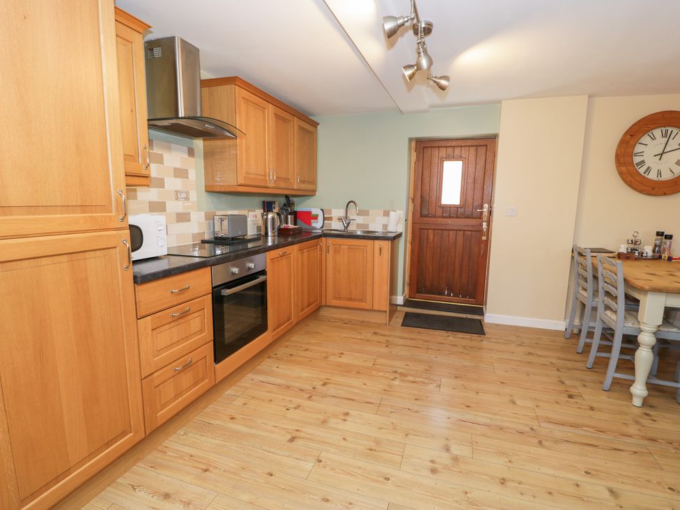 A kitchen with wooden cabinets and appliances at Owl Cottage in Llangollen
