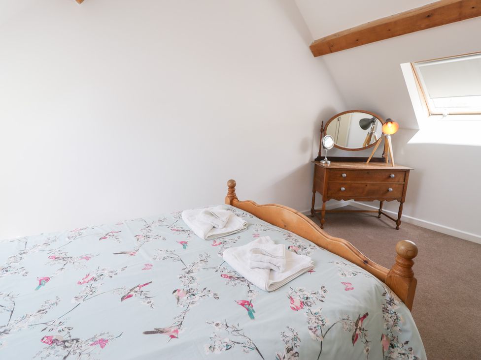A bedroom with a bed and dressing table at Owl Cottage in Llangollen