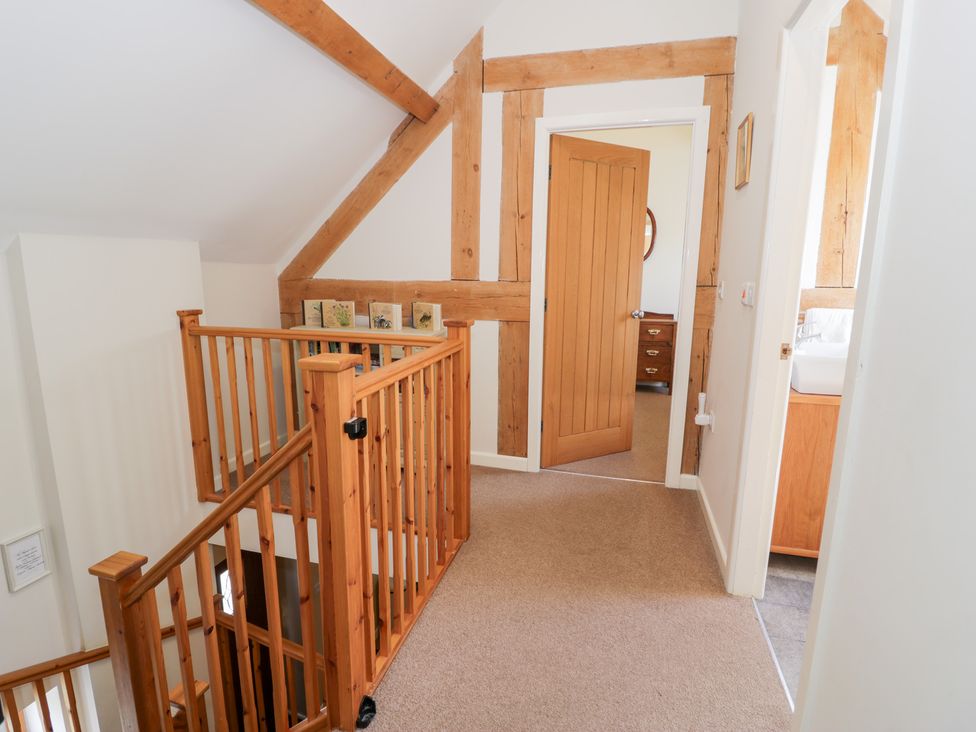 A hallway with a staircase and doorways at Owl Cottage in Llangollen