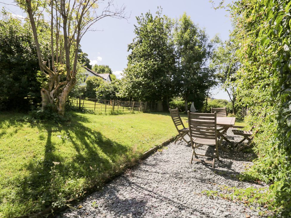 A garden with a table and chairs on a gravel path at Owl Cottage in Llangollen