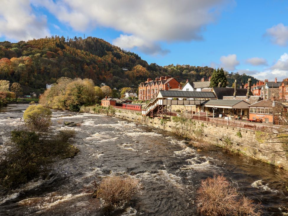 A view of a river with buildings and trees at Owl Cottage in Llangollen