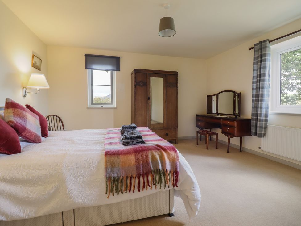 A bedroom with a bed, wardrobe, and desk at Upper Pandy Farm in Welshpool