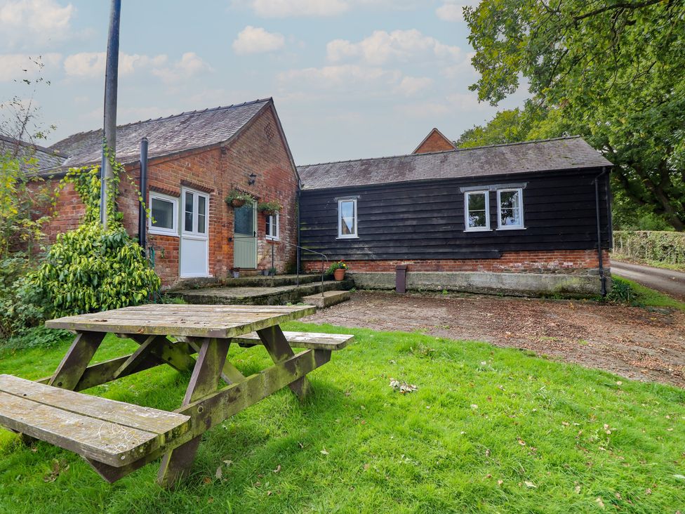 An outdoor view of a house with a picnic table at Upper Pandy Farm in Welshpool