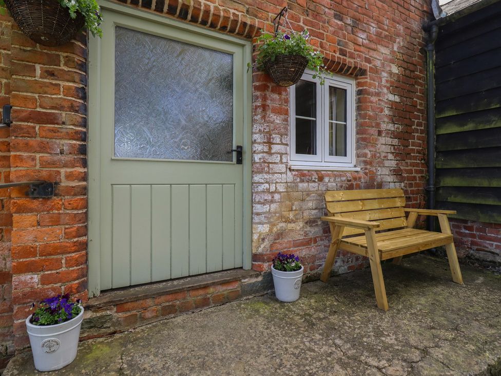 An entrance with a green door, window, wooden bench, and planters at Upper Pandy Farm, Berriew near Welshpool